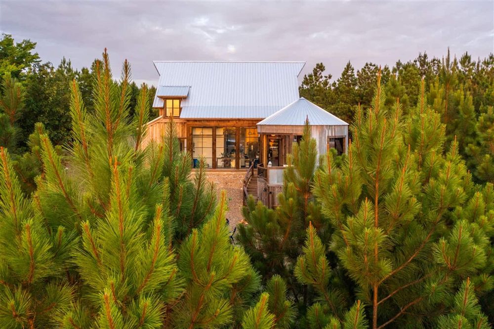 Blue Ridgetop cabin with its silo-shaped tower through the pines at golden hour